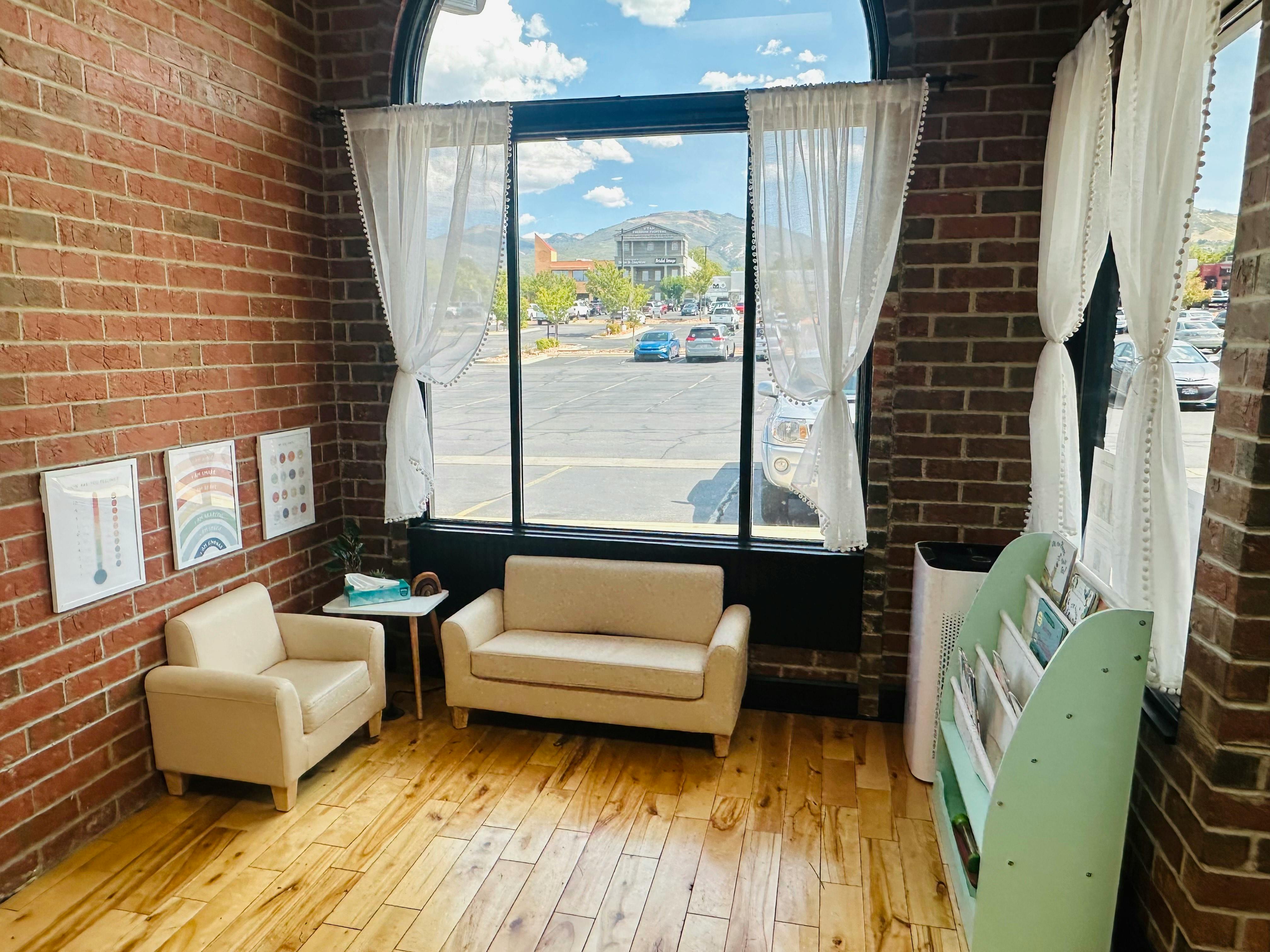 Waiting room with two couches and a large window overlooking a street