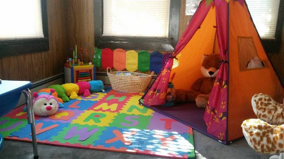 Playroom with colorful alphabet mat, stuffed toys, and a play tent