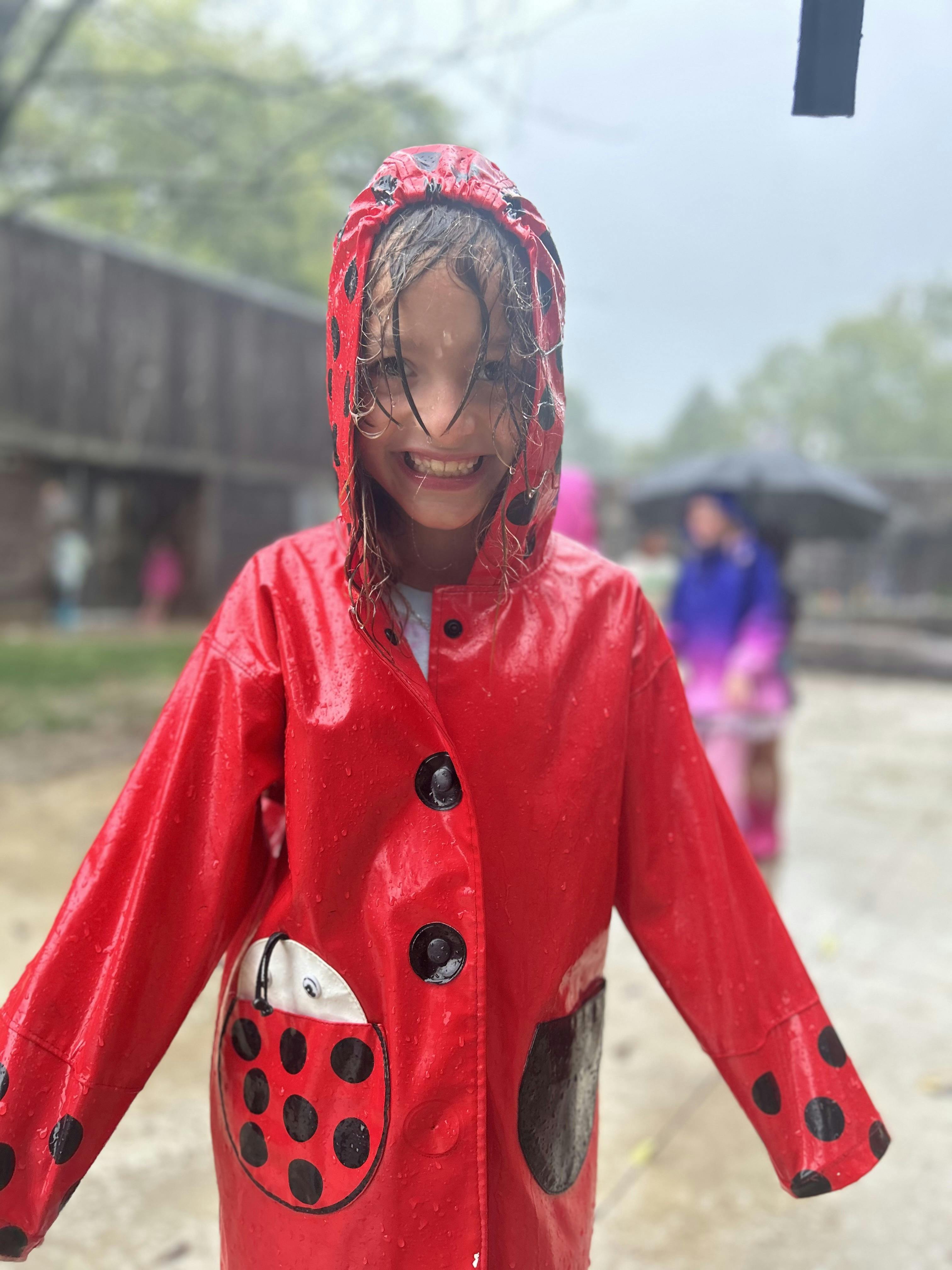 Child in a red ladybug raincoat in the rain