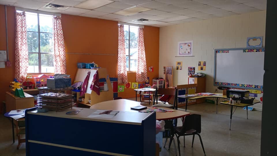 Empty classroom with tables, chairs, and a whiteboard