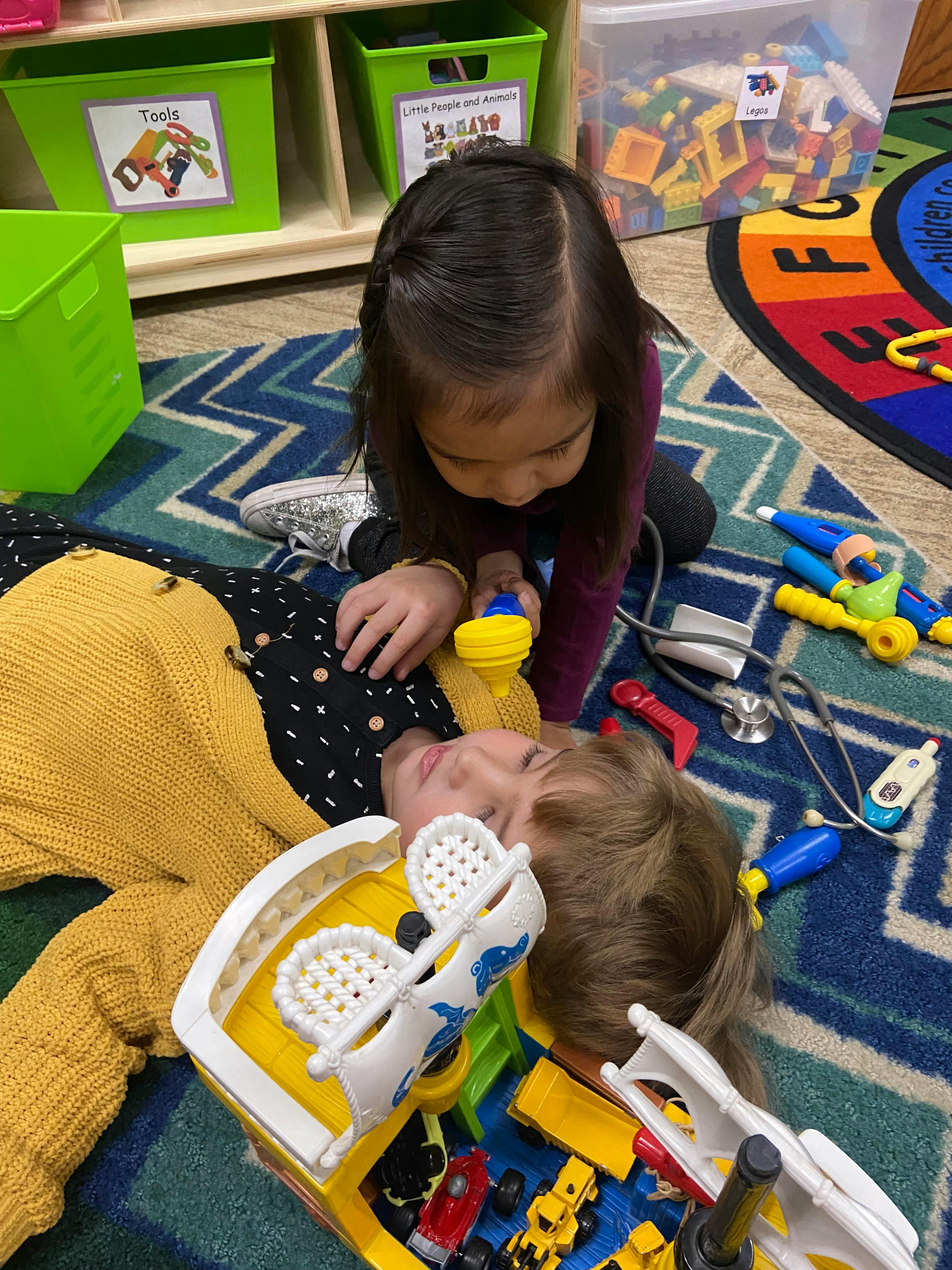Child playing with toy medical tools on another child