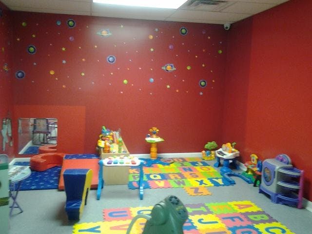 Playroom with red walls, alphabet floor mats, and various toys