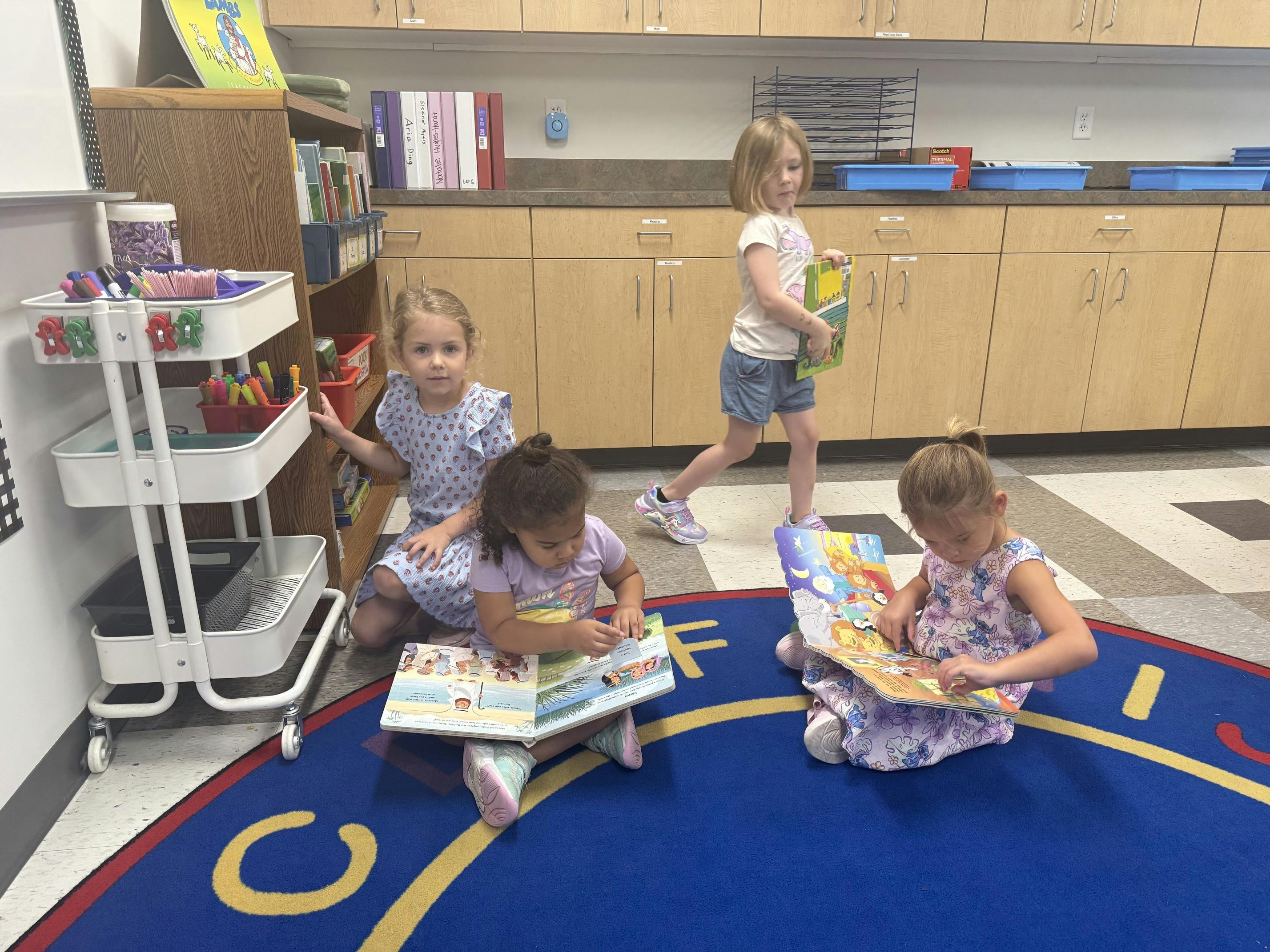Children reading books on a rug in a classroom