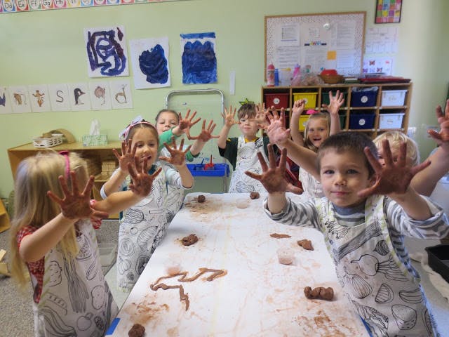 Children with messy hands raised in a classroom