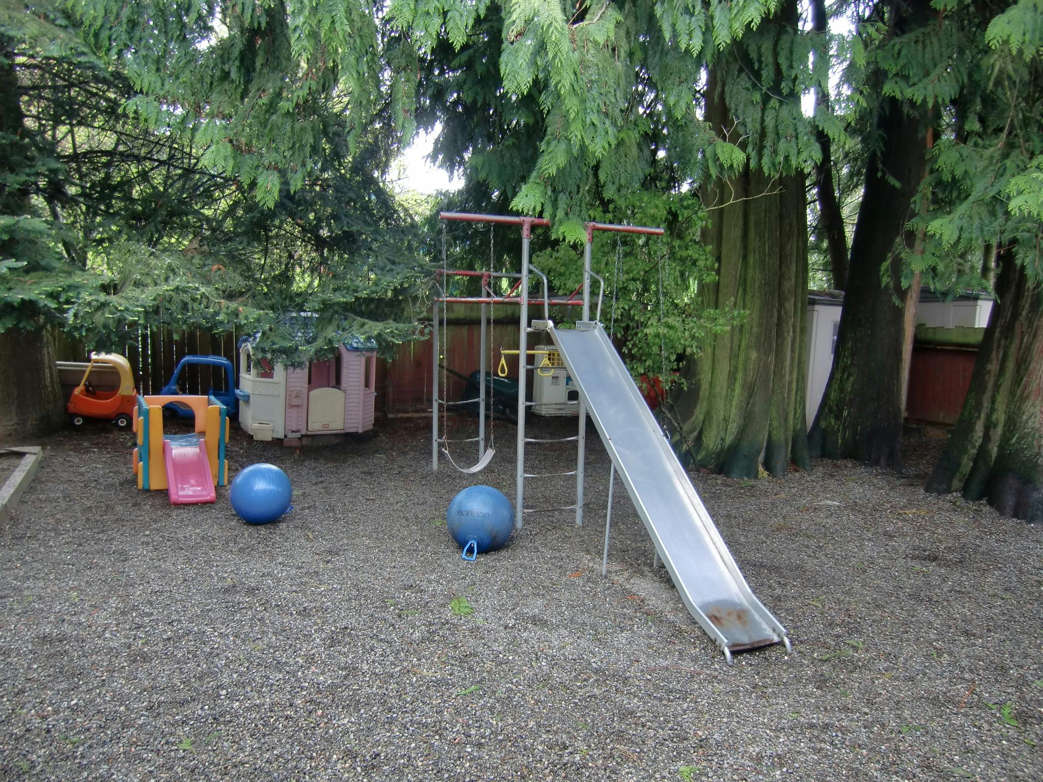 Playground with slide, swings, playhouse, and ride-on toys