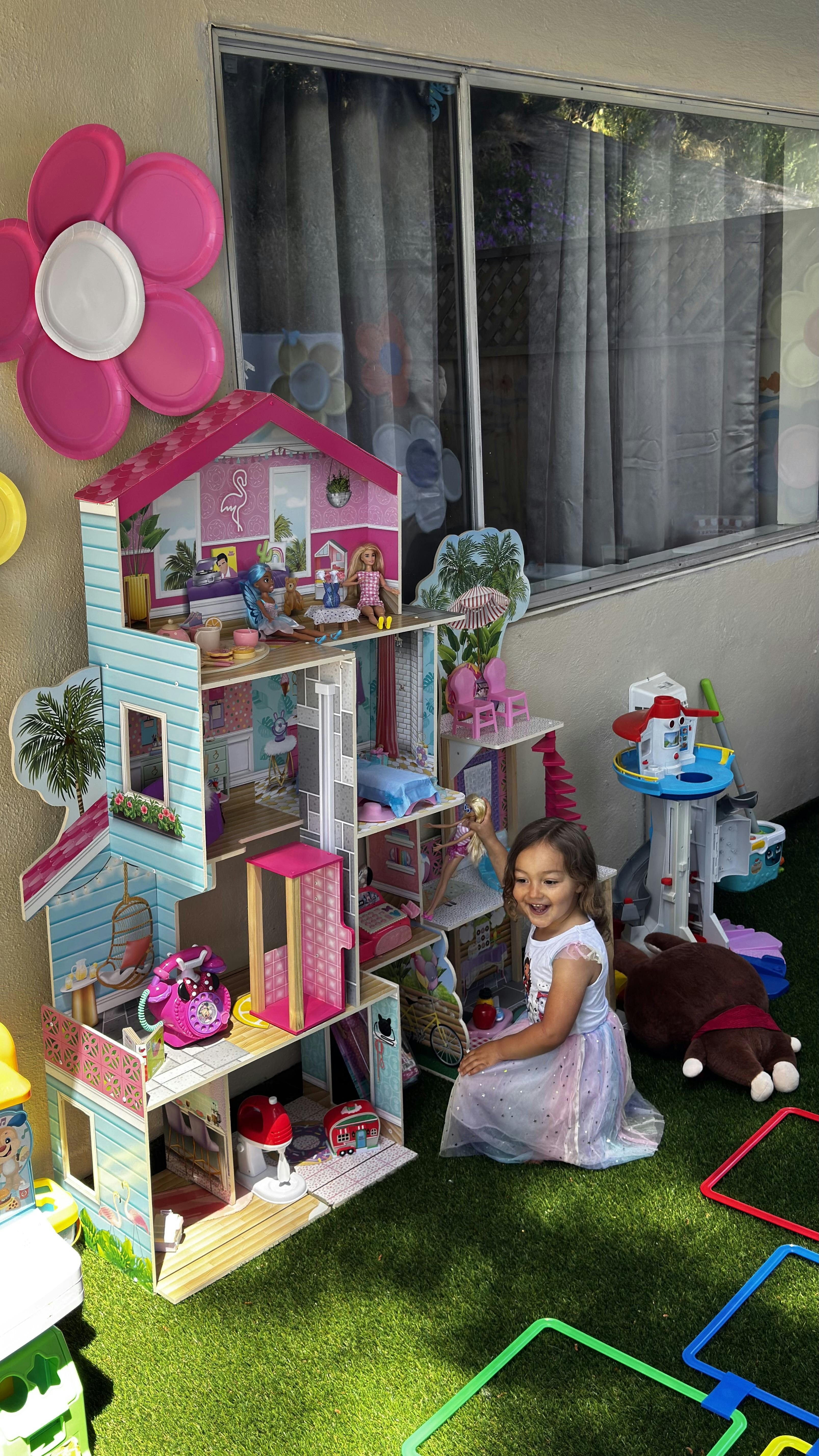 Child playing with a large dollhouse outdoors