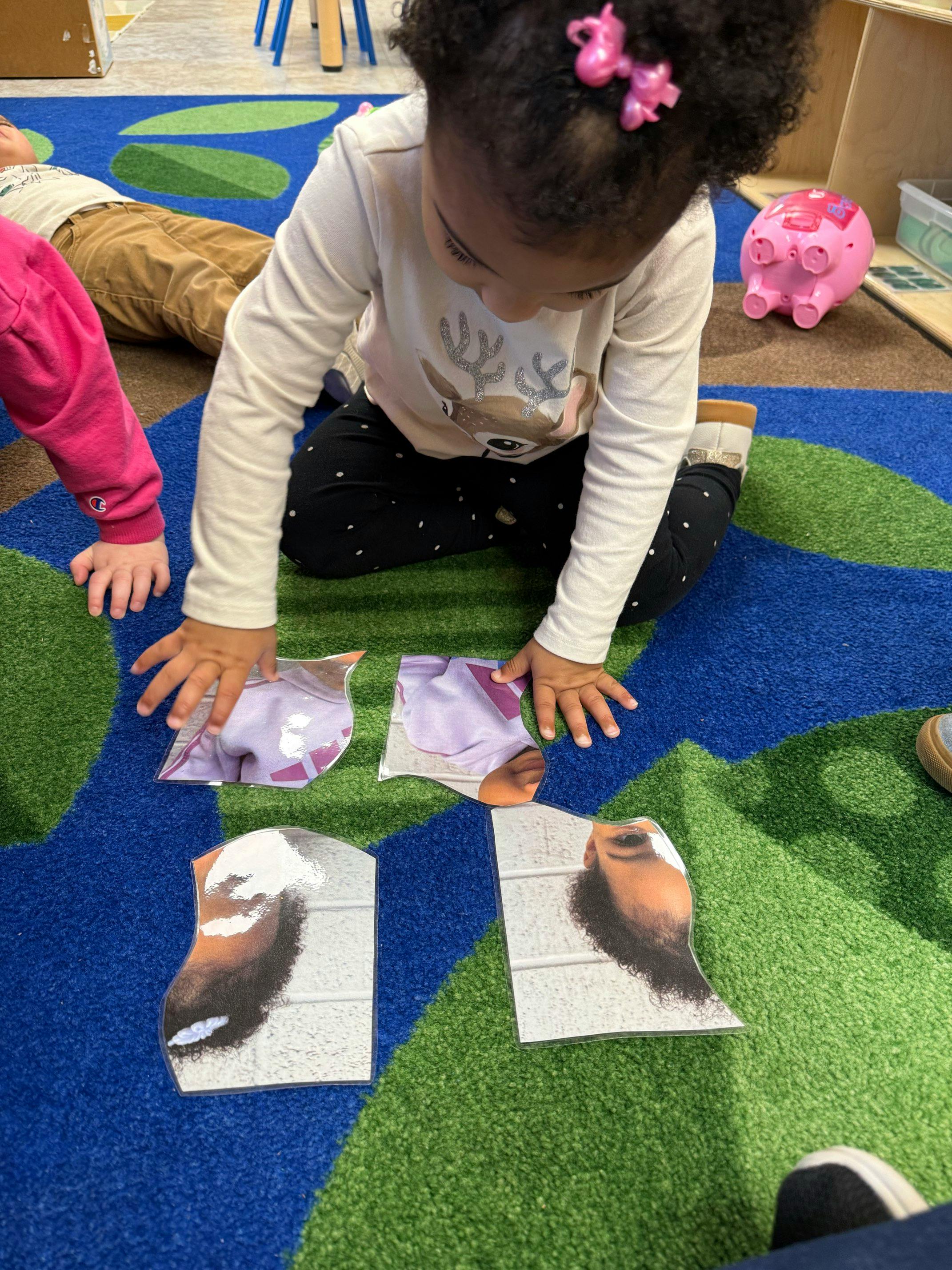 Child on a patterned rug assembling large puzzle pieces with faces on them