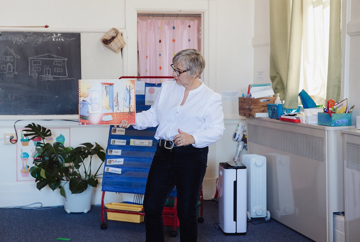 Person holding an open book in a classroom