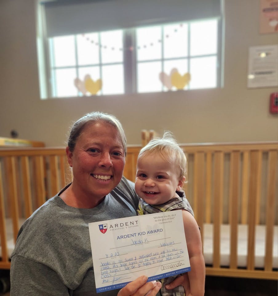Person holding a child and a certificate that reads "Ardent Kid Award"