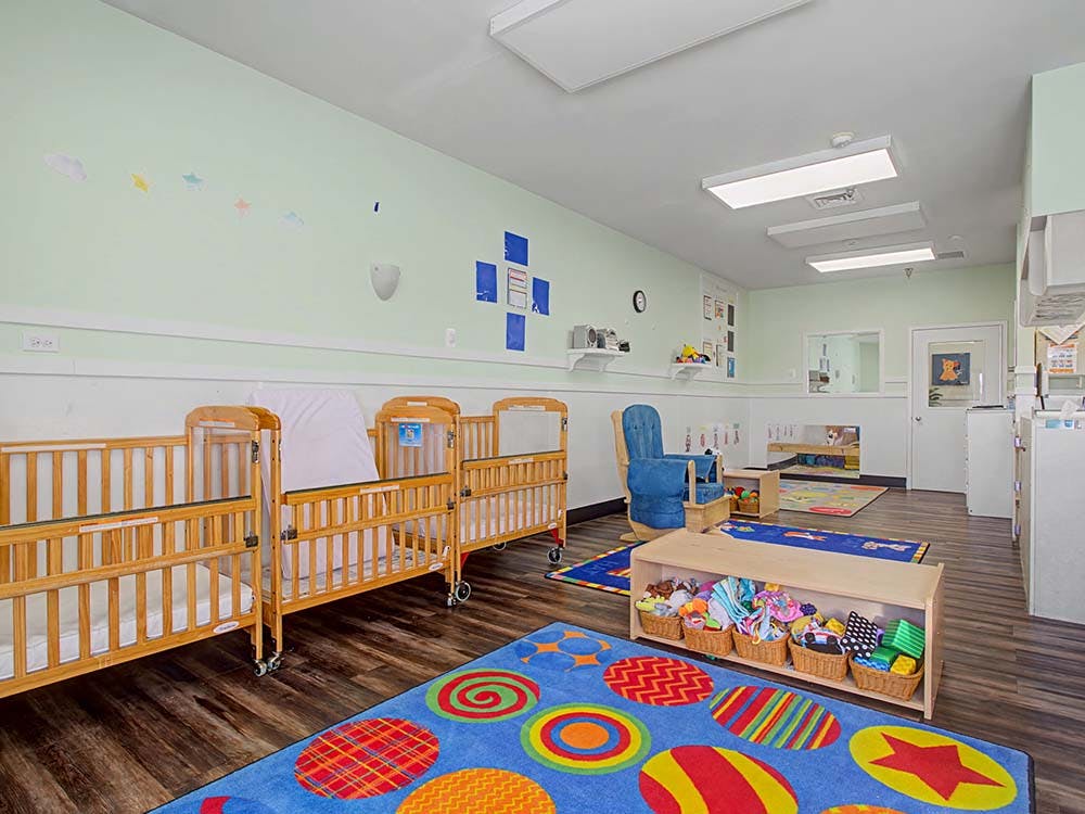 Baby cribs and colorful rugs in a brightly lit room