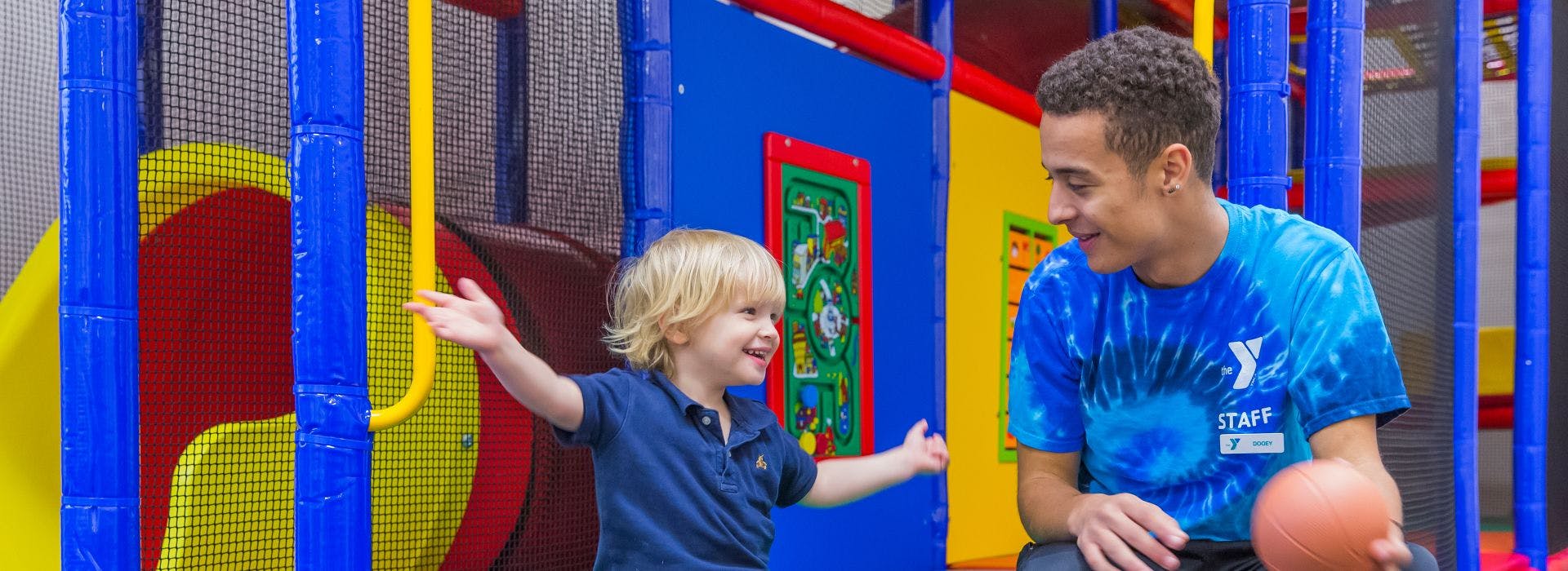 A person in a staff shirt and a child playing with a basketball