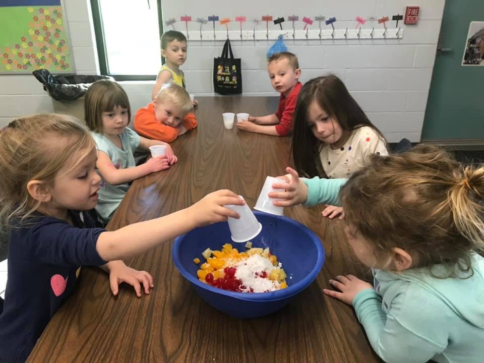 Children at a table preparing food in a bowl