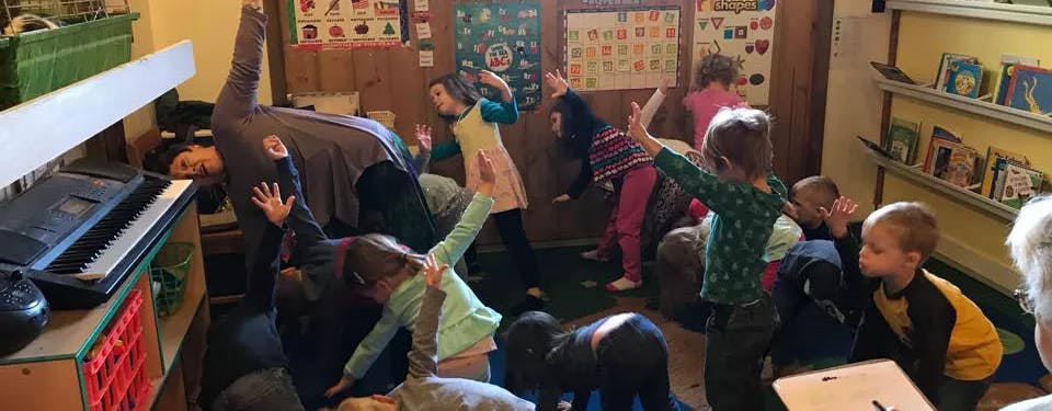Children in a classroom with arms raised
