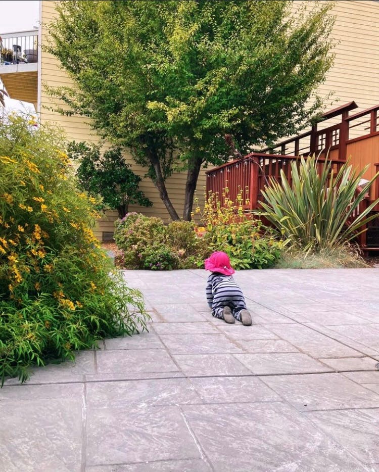 Child in a pink hat crawling on a patio
