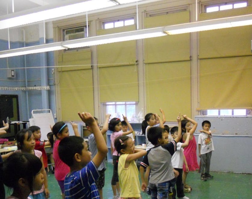 Children in a classroom raising their hands