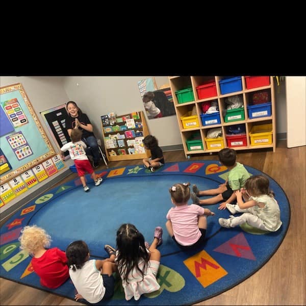 Adult and children sitting on a rug in a classroom