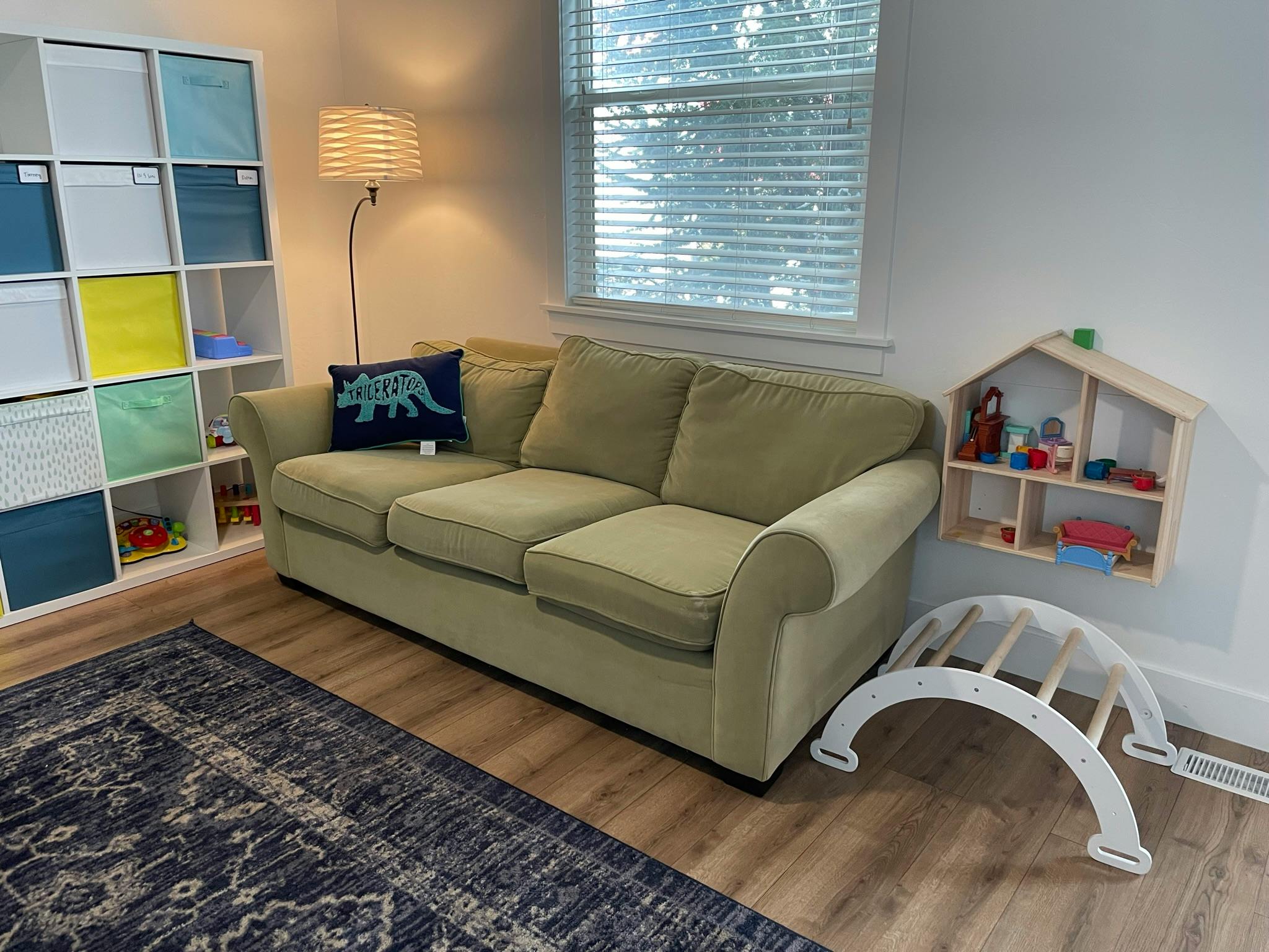 Sofa with a dinosaur pillow, storage shelves, and a dollhouse shelf