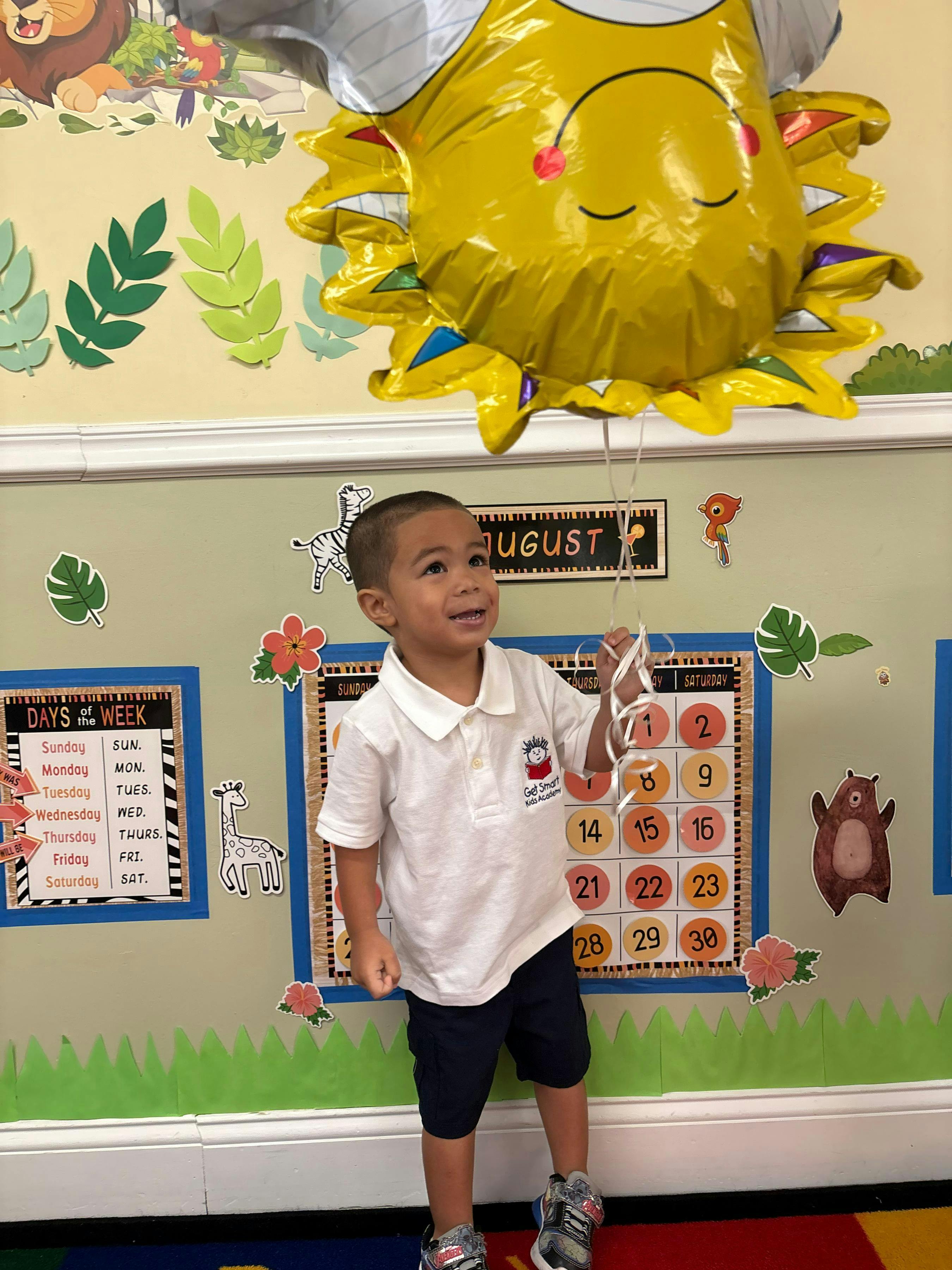 Child holding a sun-shaped balloon in a classroom