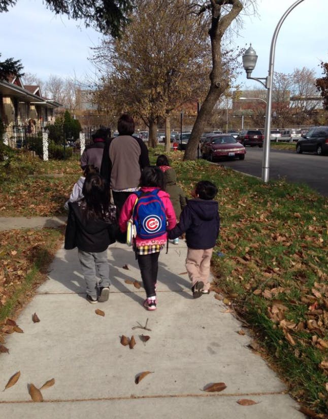 Group of people and children walking on a sidewalk