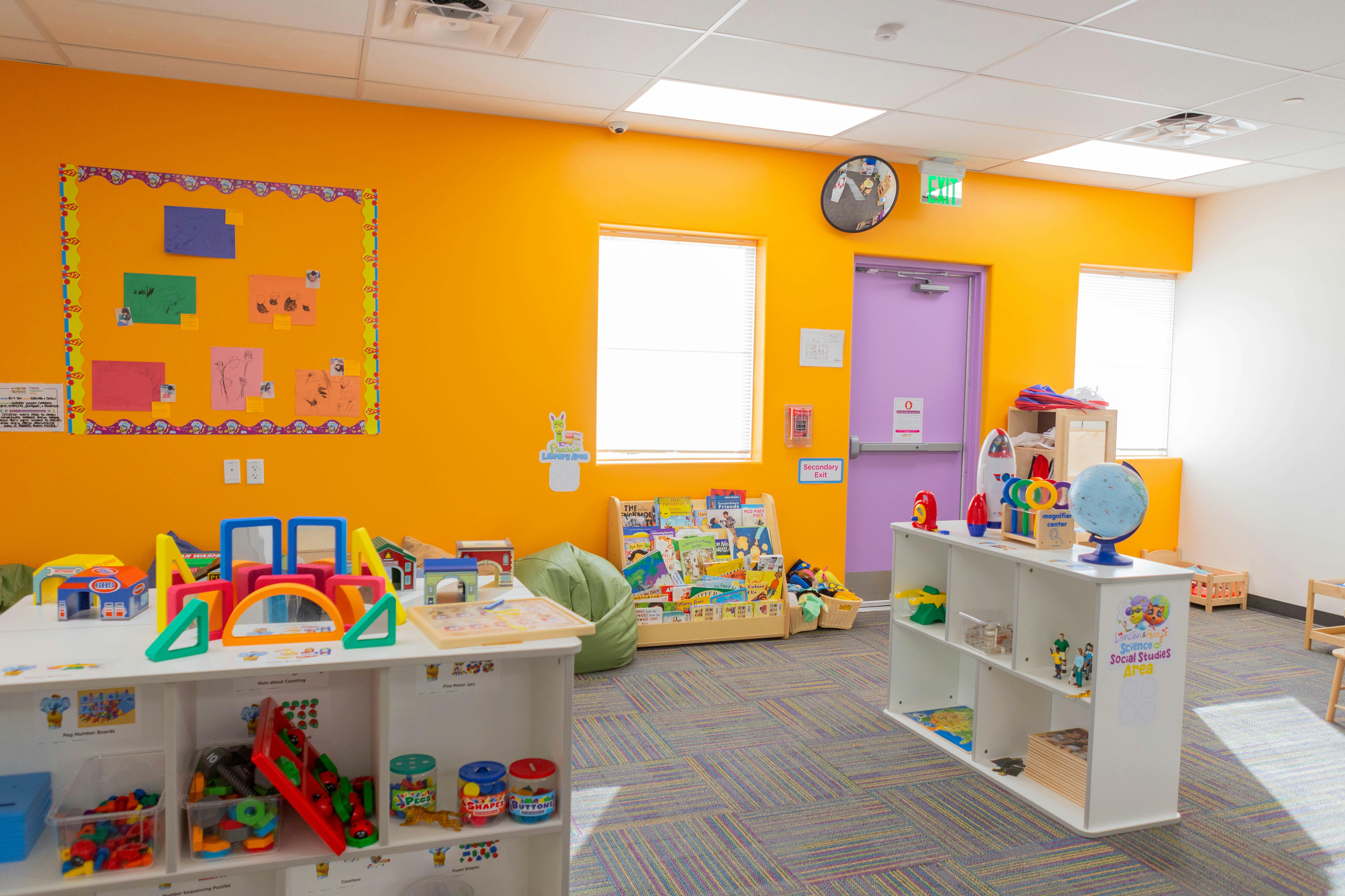 Playroom with orange walls, toys on tables and shelves, and a purple door