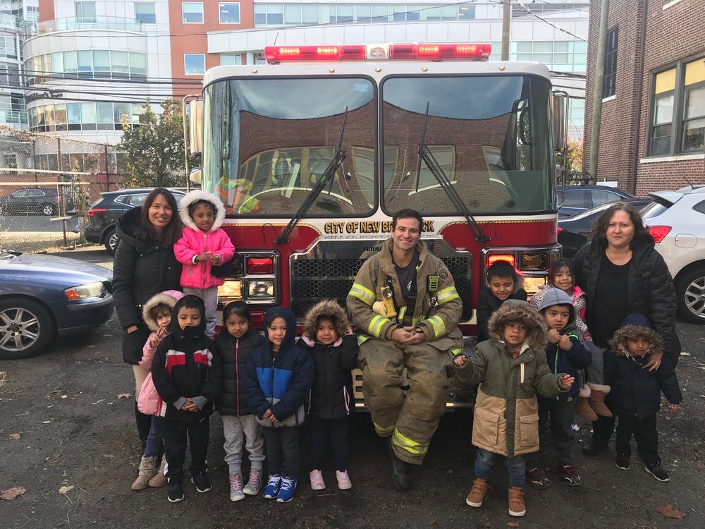 Firefighter and adults with children in front of a fire truck