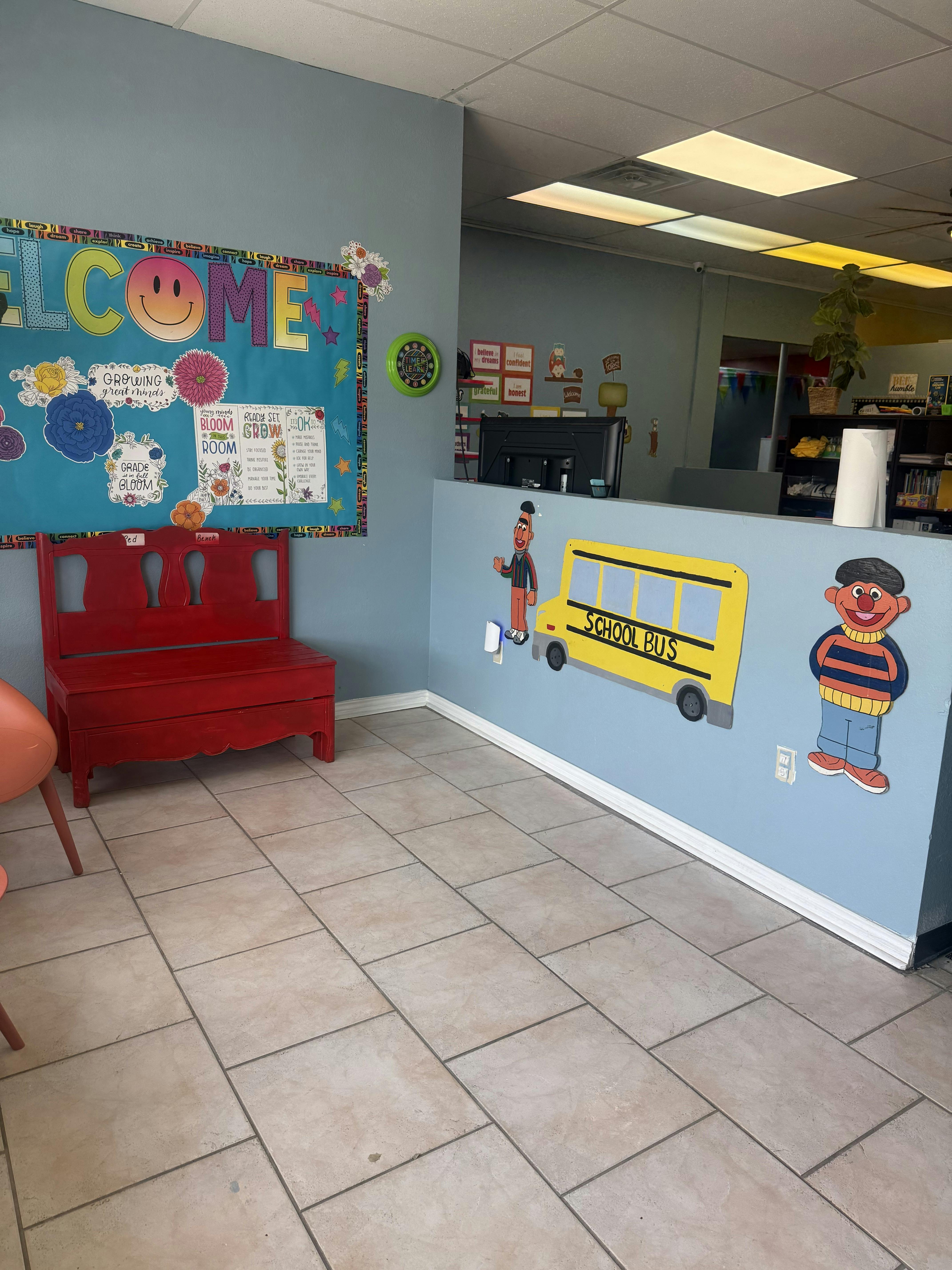 Classroom with a welcome board, red bench, and school bus decorations