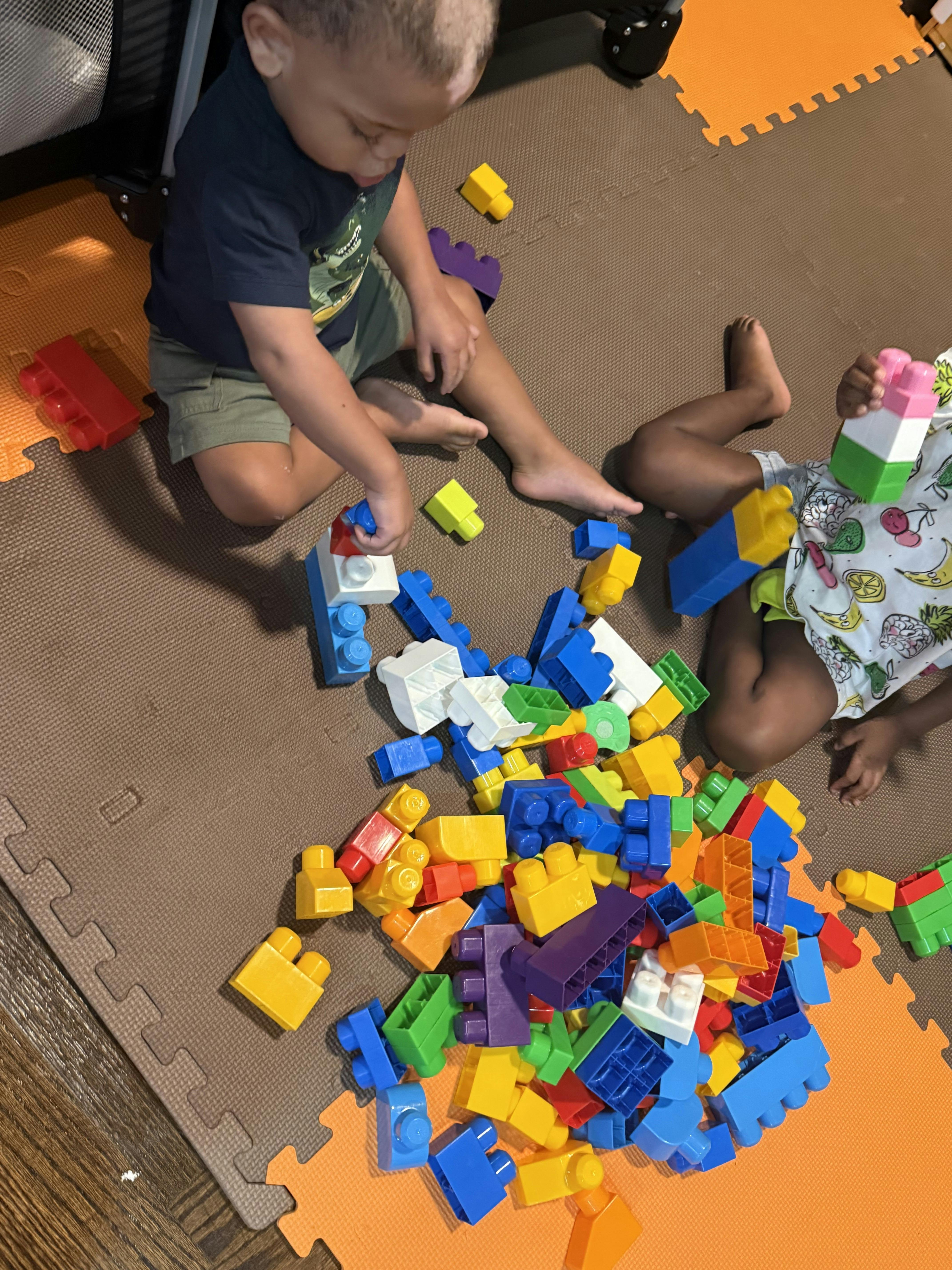 Two children playing with colorful building blocks on a mat
