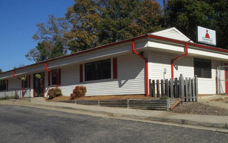 Building with white siding and red gutters, Kindercare sign on the roof
