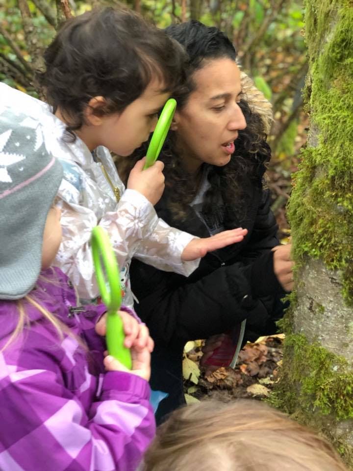 Person and child looking at moss on a tree trunk with a magnifying glass