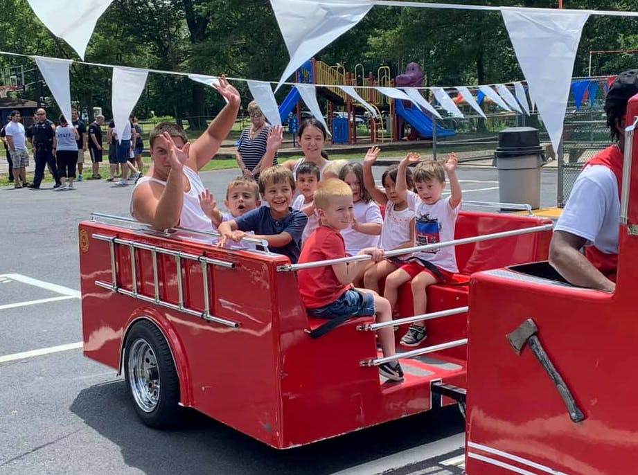 People and children riding in a red fire truck