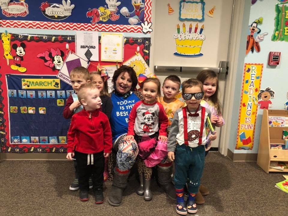 Adult and multiple children posing in a classroom