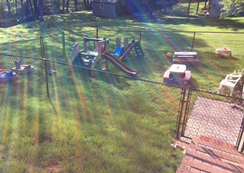 Playground with slides and swings in a fenced yard