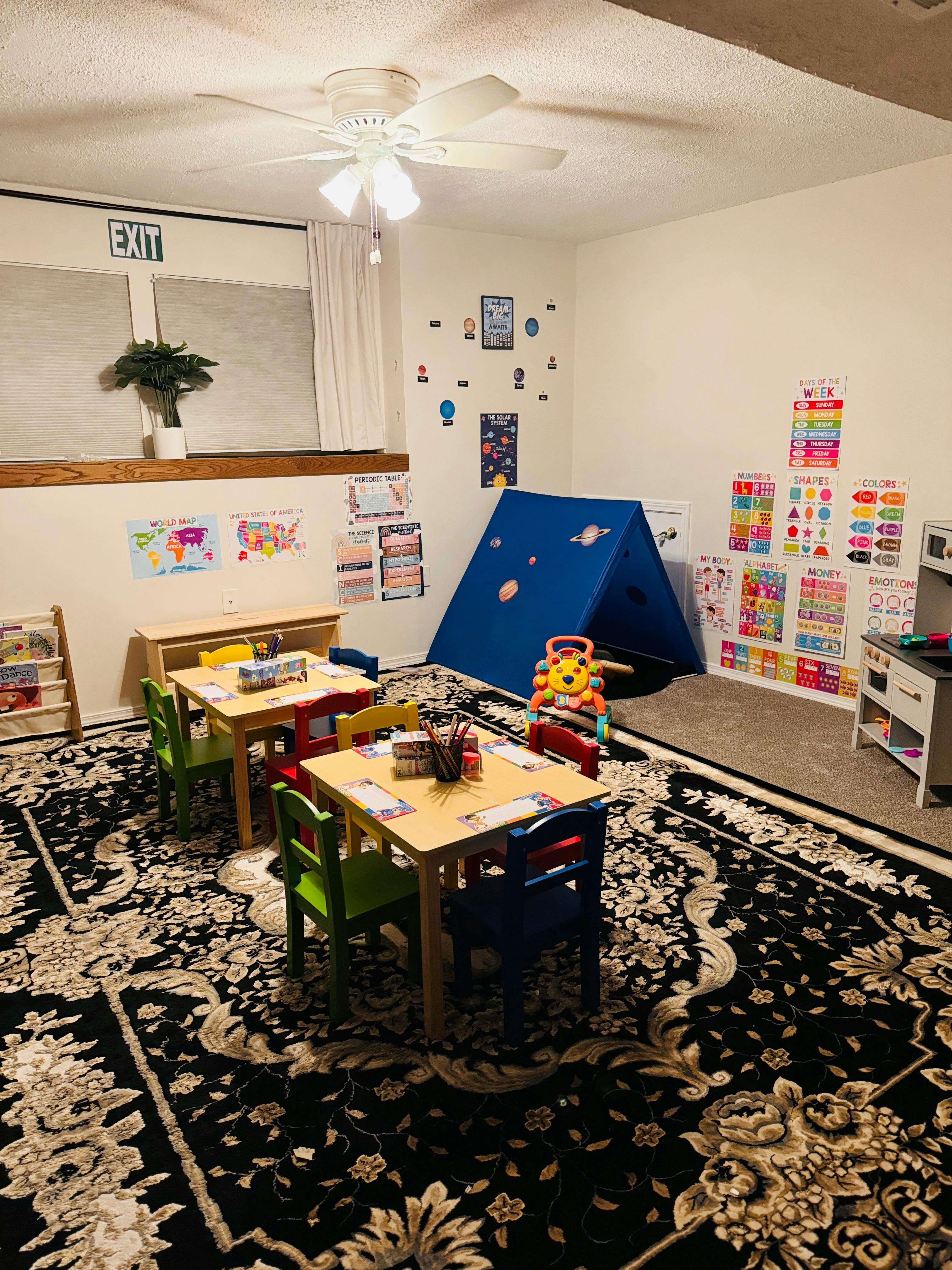 Classroom with small tables and chairs, a blue tent, and educational posters