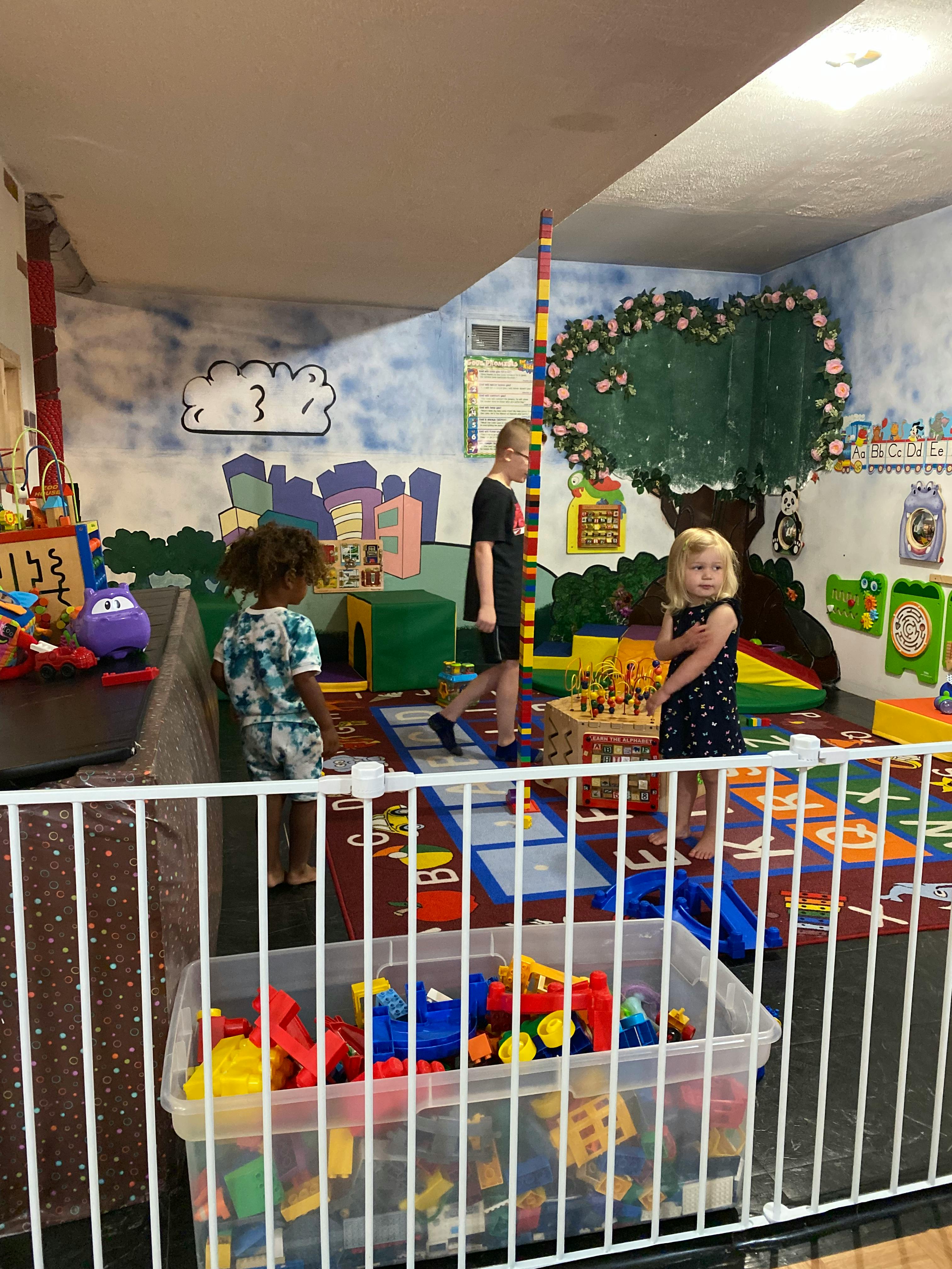 Three children playing in a colorful room with toys and murals