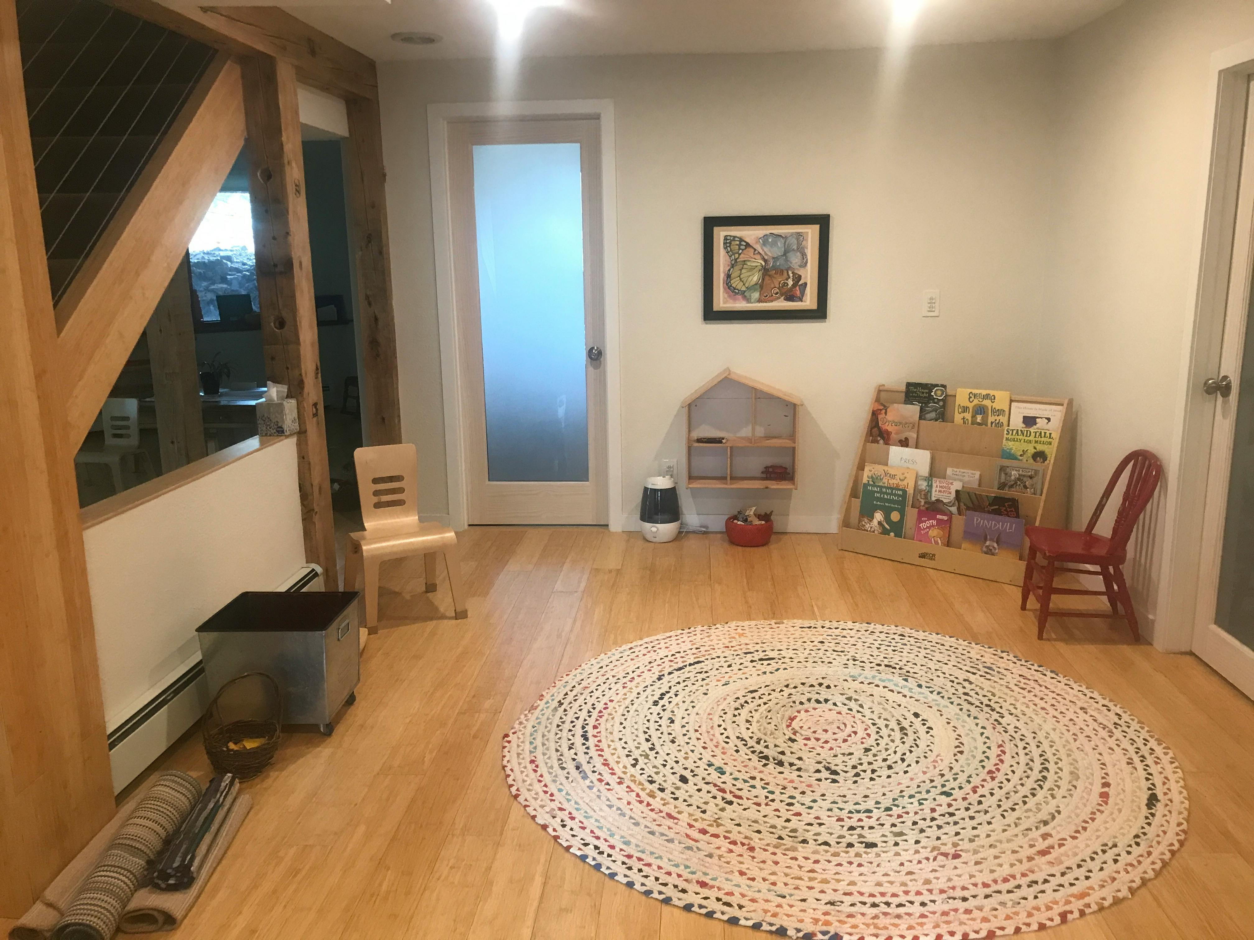 Room with a round rug, small chairs, and bookshelves