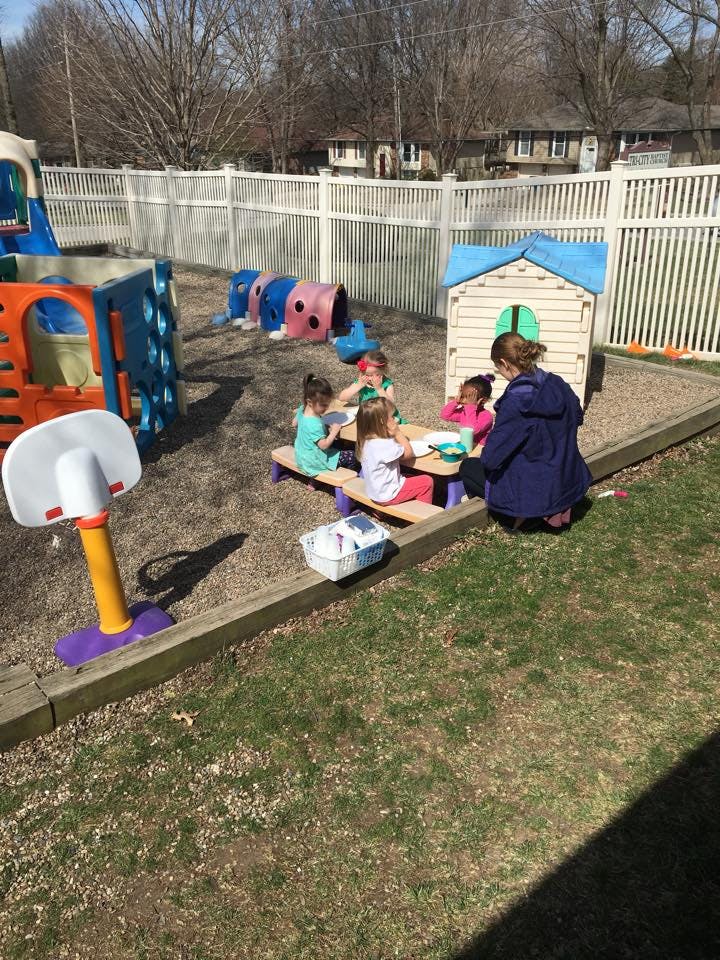 Adult and children sitting at a picnic table on a playground