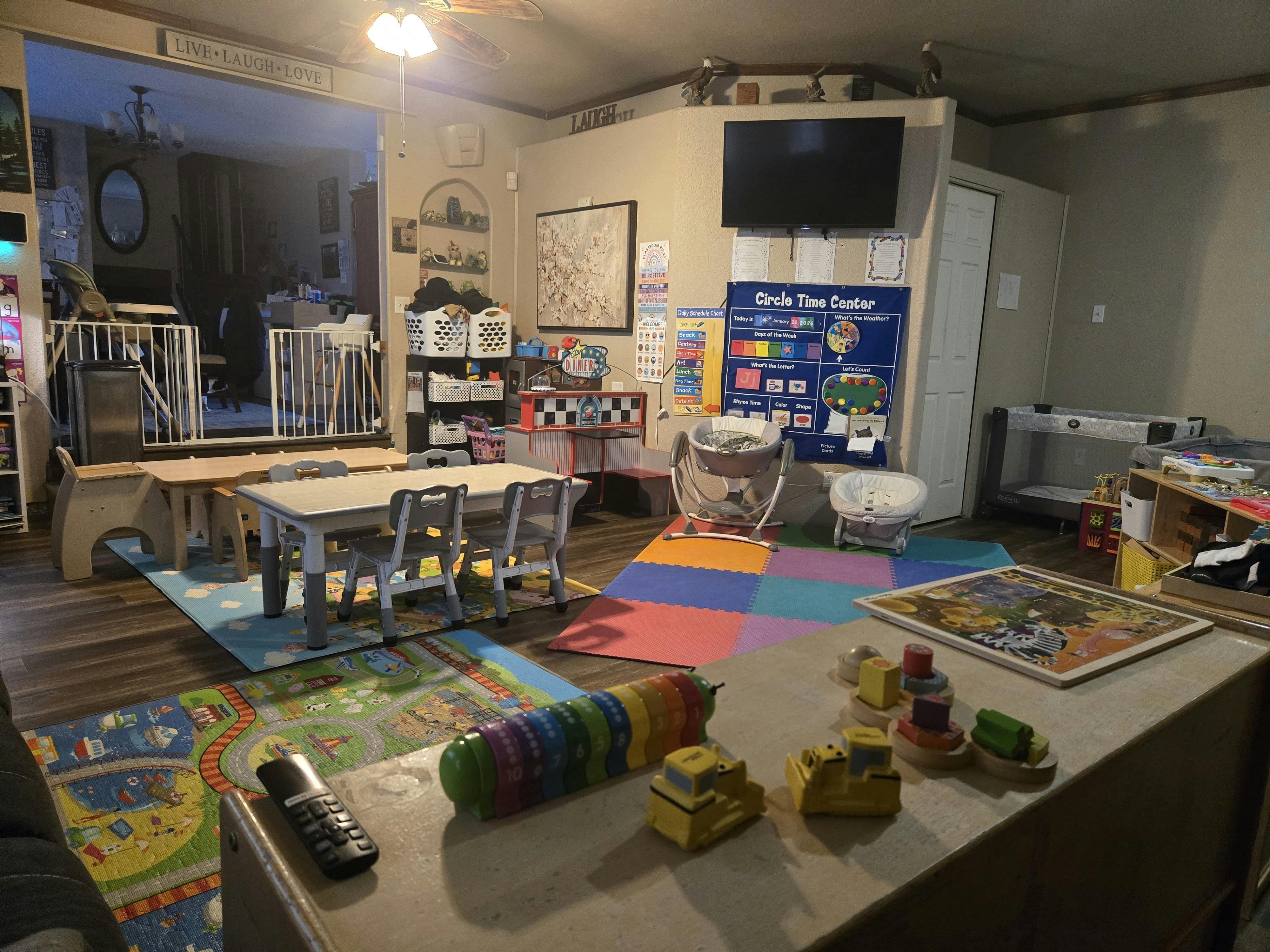 Children's play area with tables, rugs, and a daily schedule chart