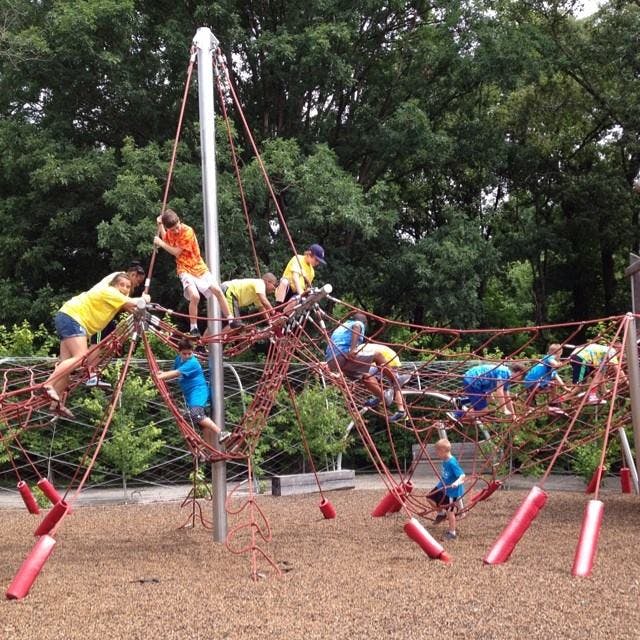 Children climbing on a large rope net structure at a playground
