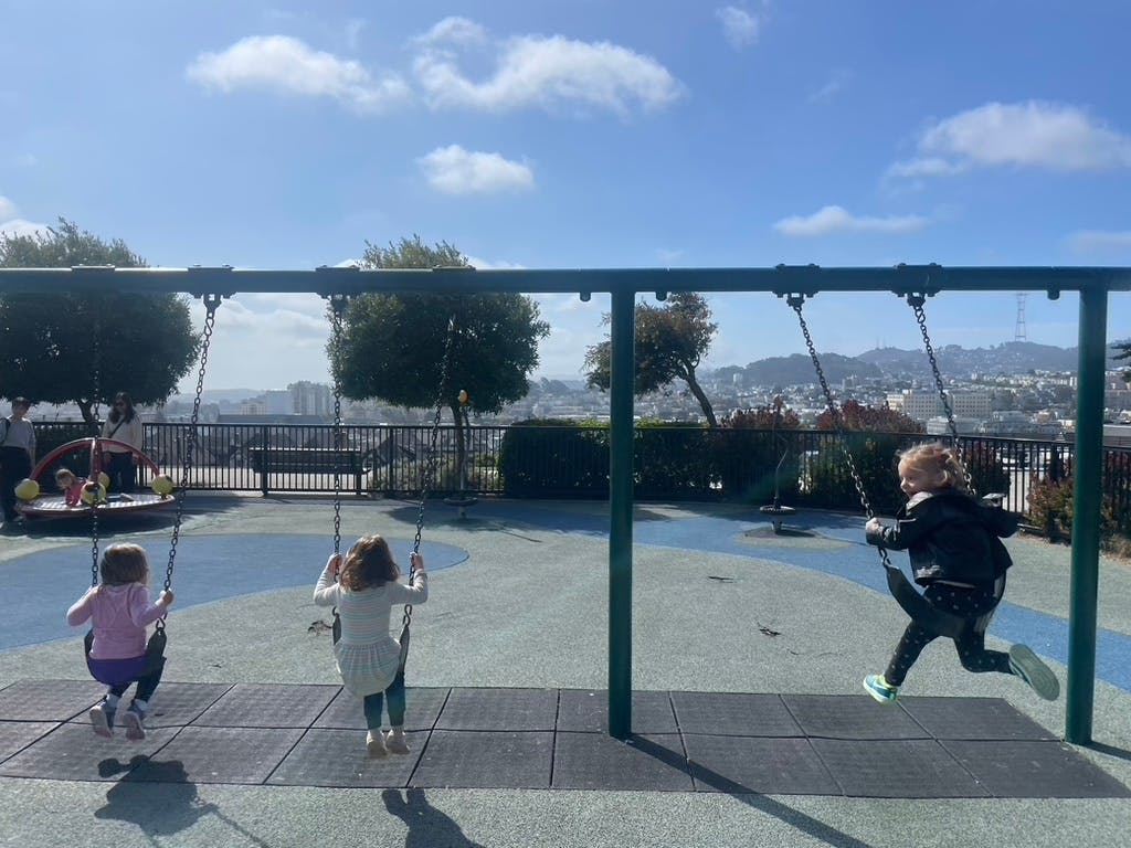 Three children on swings at a playground