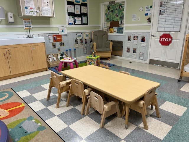 Children's classroom with small table and chairs, toys, and a changing station