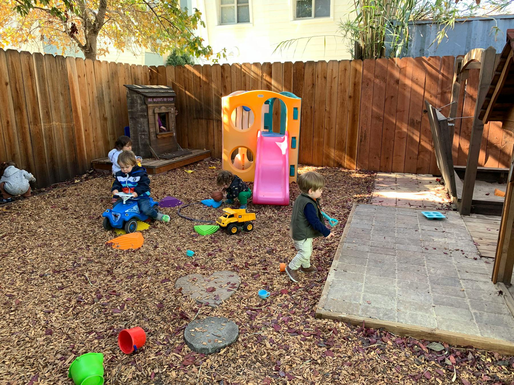 Children playing in a wood chip playground with toys and play structures