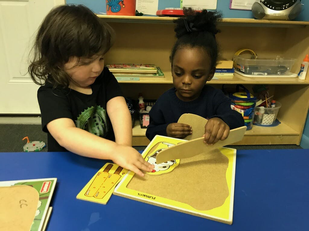 Two children playing with puzzles at a table