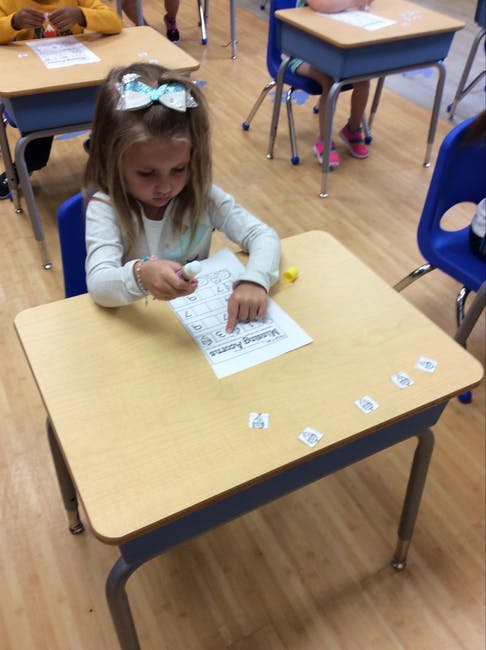 Child at a desk working on a paper with small cutouts