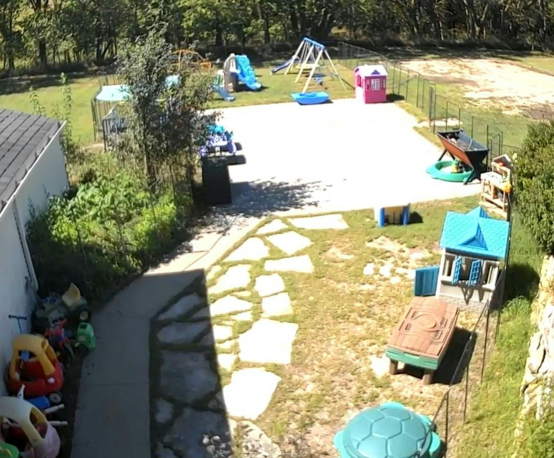 Backyard playground with toys and play structures on a patio and lawn