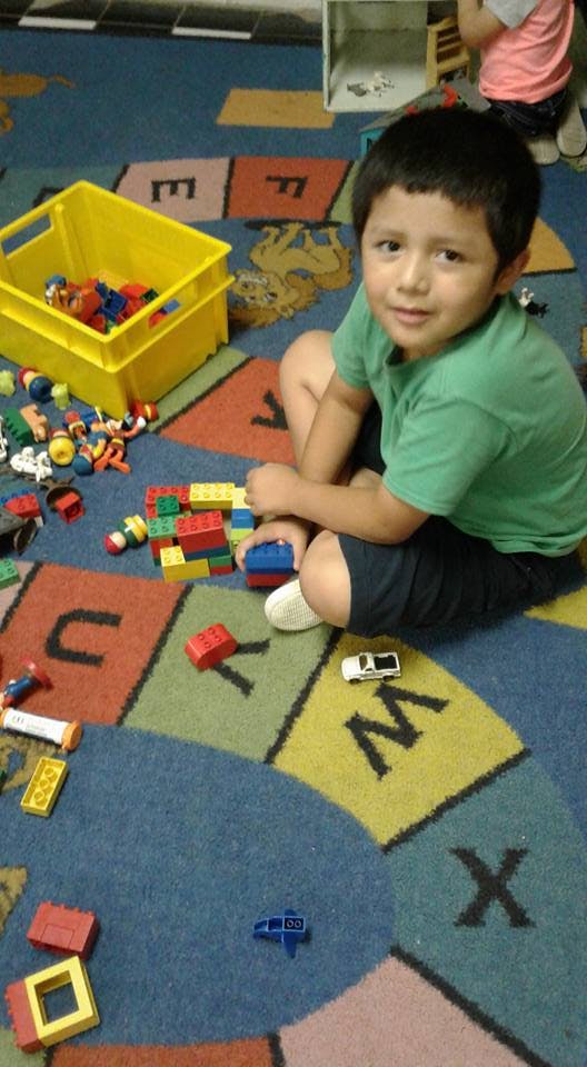 Child sitting on a rug with building blocks and toys