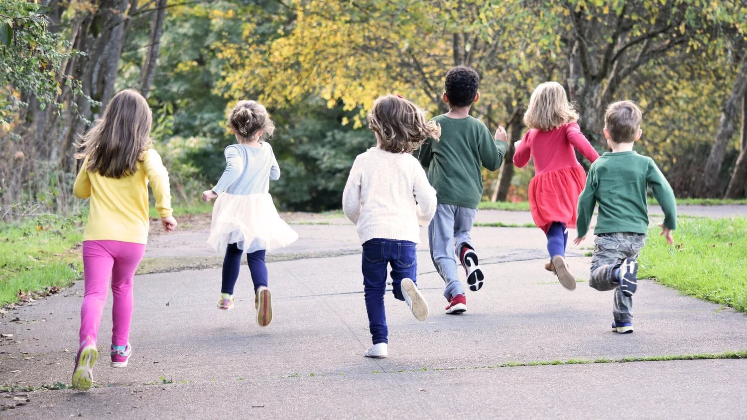Group of children running away from the camera on a paved path