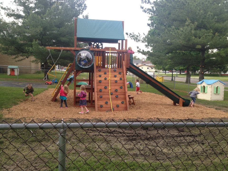 Children playing on a wooden playground structure with slides and swings