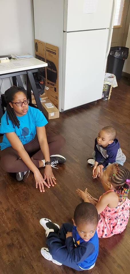 Person sitting on floor with three children