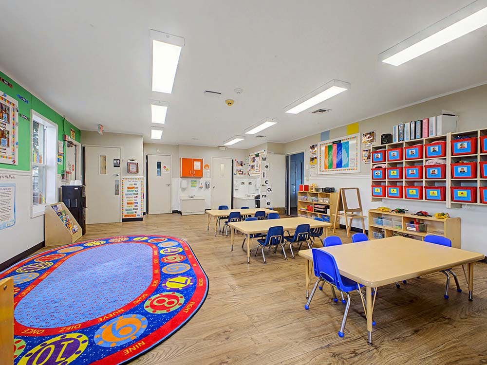 Classroom with small tables, chairs, and a colorful rug