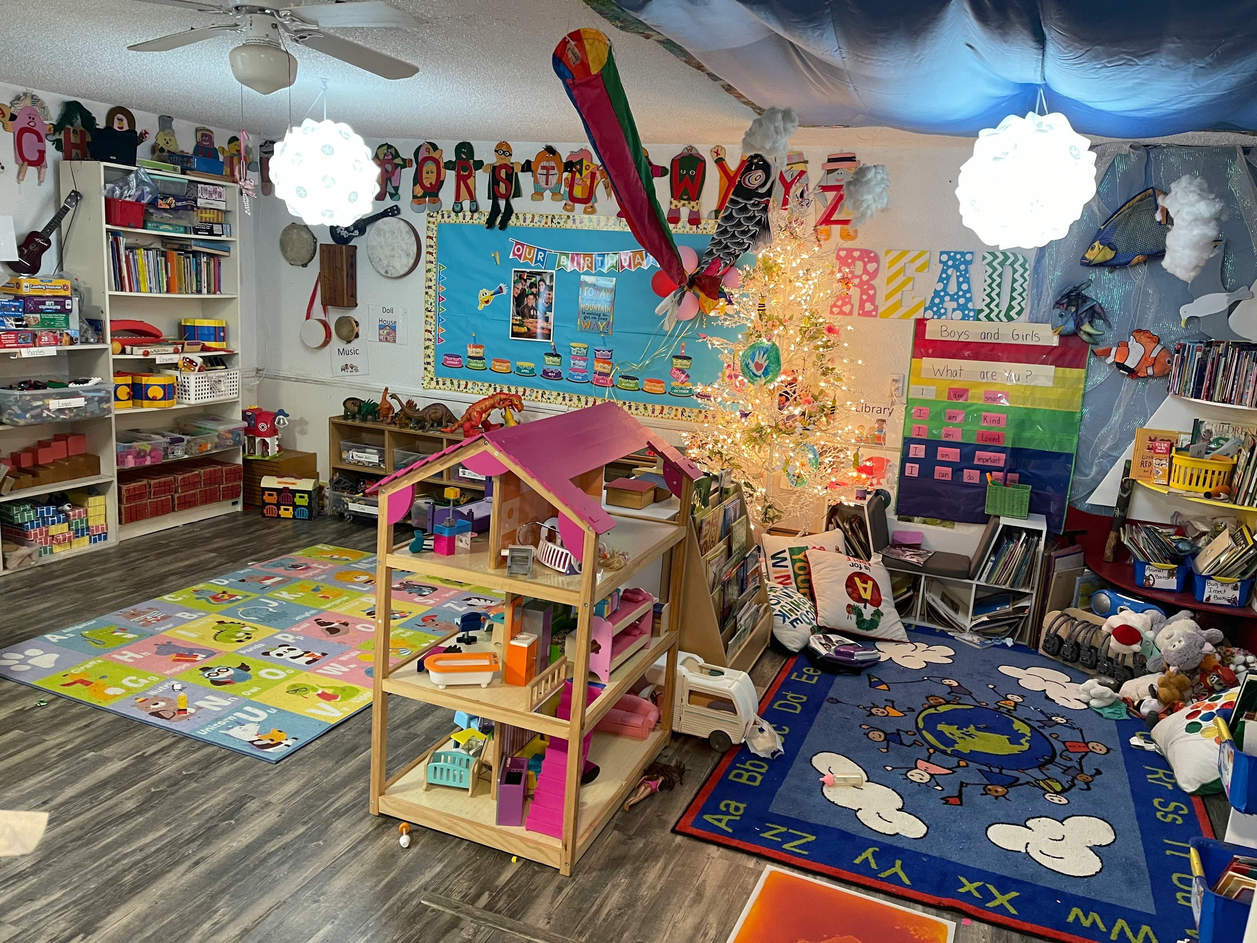 Playroom with a dollhouse, colorful rugs, and shelves of a Christmas tree